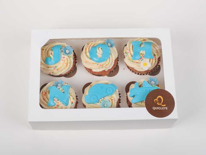 Six unique cupcakes made by Quigleys bakery with John, a car and an aeroplane icing detailing